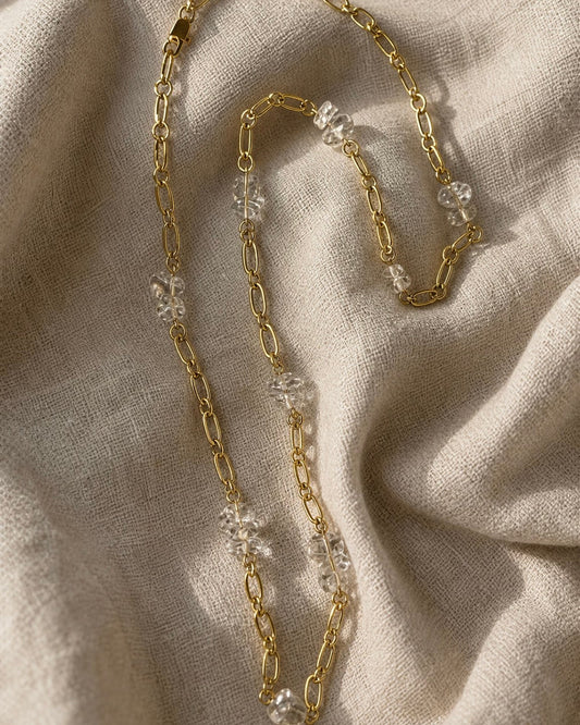Gold chain necklace with clear quartz nuggest on beige fabric