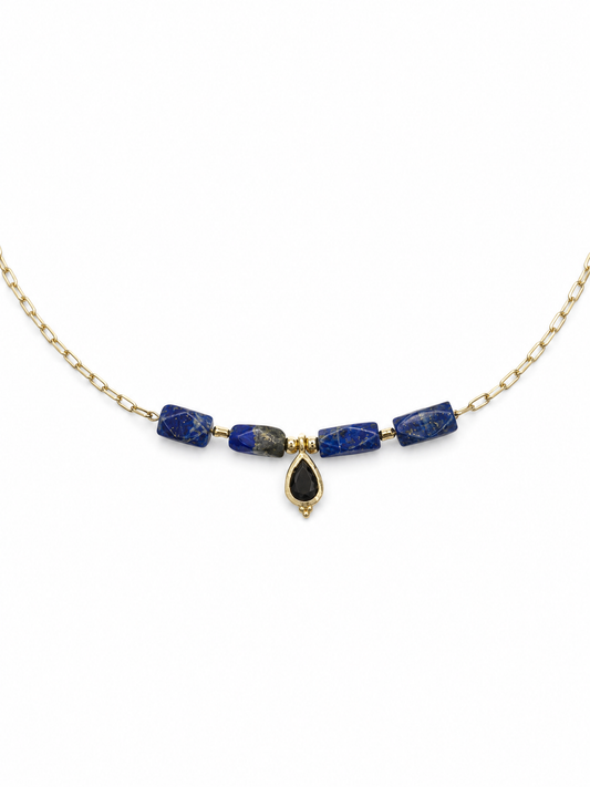 A gold chain necklace featuring four blue lapis lazuli beads and a central teardrop-shaped black stone pendant, displayed on a clean white background.